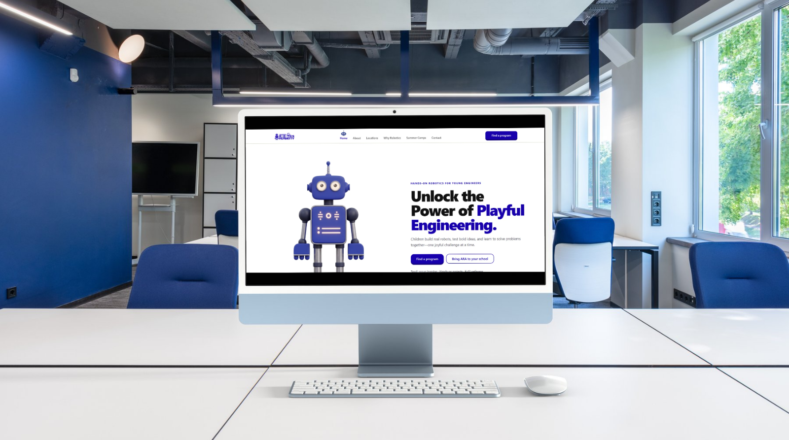 American Robotics Academy website displayed on an iMac in a bright blue-and-white robotics classroom